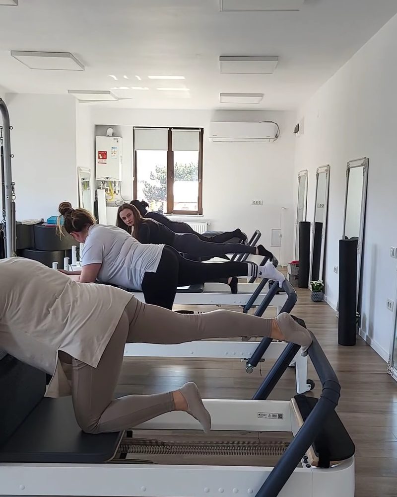Clase pe reformer într-o sală luminoasă, cu ferestre mari
